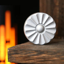 Load image into Gallery viewer, Silver daisy magnetic sound coin displayed on shelf with warm light