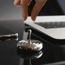 Load image into Gallery viewer, finger starting stainless steel spinning top on desk surface

